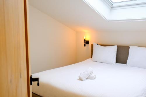 a bedroom with a white bed with a skylight at Herberg de Boelekeerl in Halle