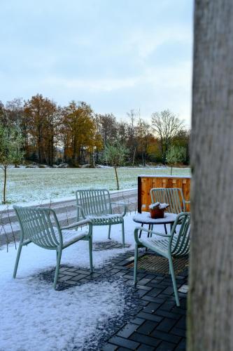 two park benches and a table covered in snow at Herberg de Boelekeerl in Halle