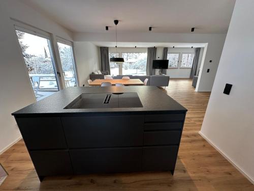 a kitchen with a black island in a living room at Gartensee Chalet in Seeshaupt in Seeshaupt