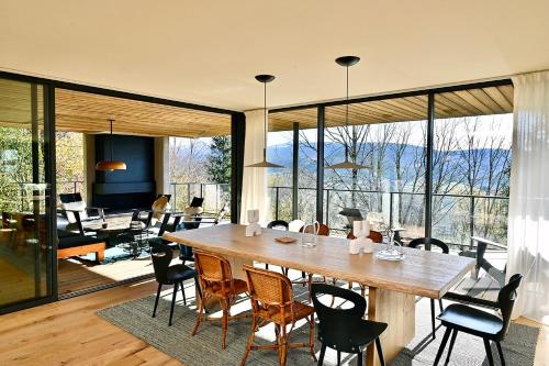 a dining room with a large wooden table and chairs at L'Avancée Chalet contemporain au coeur du Sancy AUVERGNE in Murat-le-Quaire