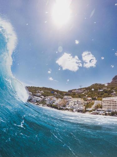 a wave in the ocean with a city in the background at Arc Guest House in Cape Town
