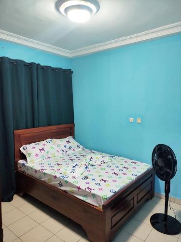 a bedroom with a bed with a blue wall and a fan at YB-TECHs in Mbala