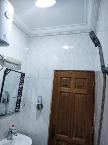 a bathroom with a sink and a wooden door at YB-TECHs in Mbala