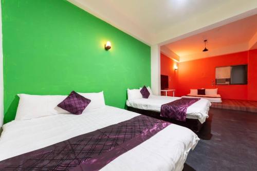 two beds in a room with a green wall at 日月潭水里東方海悅輕旅包棟 in Shuili