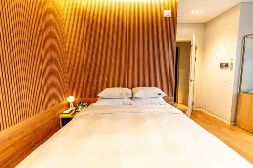 a large bed in a room with a wooden wall at Lagobaum Hotel in Sejong