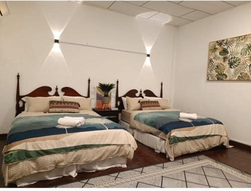 two beds in a bedroom with white walls at Soho Stay in Kuala Terengganu