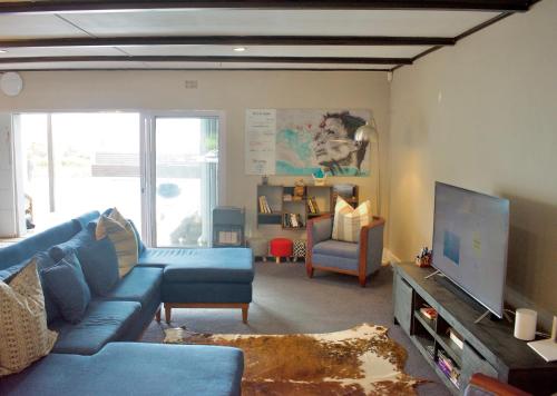 a living room with a blue couch and a tv at Seabatical in Knysna