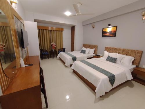 a hotel room with two beds and a flat screen tv at Sylhet Paradise Inn in Sylhet
