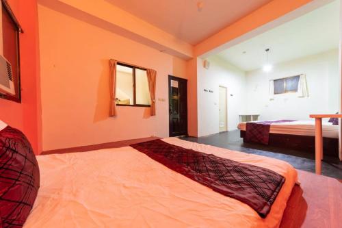 a bedroom with two beds and orange walls at 日月潭水里東方海悅輕旅包棟 in Shuili