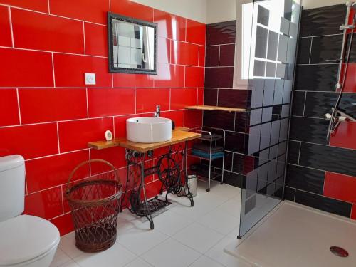 een rode badkamer met een wastafel en een douche bij maison Américan Beach in Longeville-sur-Mer