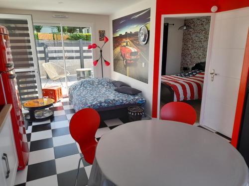 een kamer met een tafel en stoelen en een slaapkamer bij maison Américan Beach in Longeville-sur-Mer