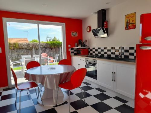 une cuisine avec des murs rouges et une table et des chaises dans l'établissement maison Américan Beach, à Longeville-sur-Mer