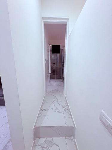 a hallway with white walls and marble floors and a mirror at Villa Life in San Donato Milanese