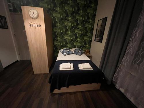 una piccola camera con un letto con asciugamani e un orologio di Apartamenty Stary Rynek 18 a Łomża