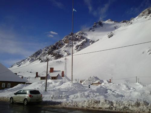 a car parked in front of a snow covered mountain at Portezuelo del Viento - Hostel de Montaña in Las Cuevas