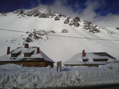 un edificio coperto di neve di fronte a una montagna di Portezuelo del Viento - Hostel de Montaña a Las Cuevas