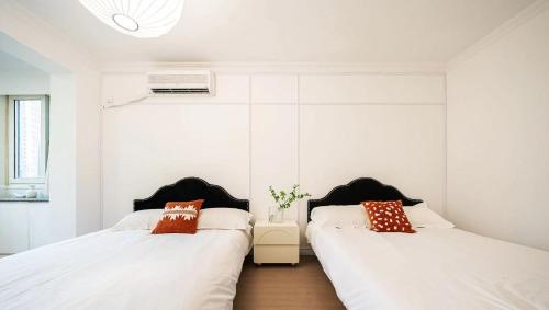 two beds in a room with white walls at Tonight Homestay West Nanjing Road Branch Shanghai in Shanghai