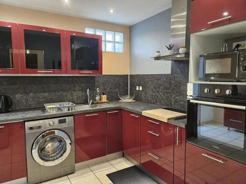 - une cuisine avec des placards rouges et un lave-linge dans l'établissement Air-conditioned house 3 bedrooms BBQ Terrace, à Toulouse