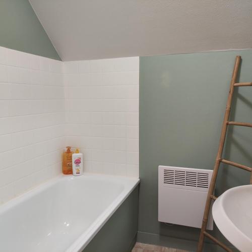 La salle de bains est pourvue d'une baignoire blanche à côté d'un lavabo. dans l'établissement maison proche plage du pouliguen baie de la baule, au Pouliguen