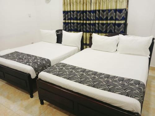 two beds sitting next to each other in a room at Treatooo Lake resort in Batticaloa