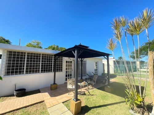 a patio with a black umbrella and some palm trees at Cozy house with sea view! in Luquillo