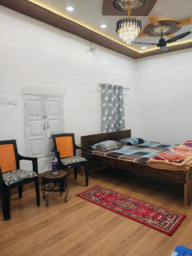a bedroom with a bed and two chairs and a rug at A ShivAngan Heritage Home Stay Near Ghat in Varanasi