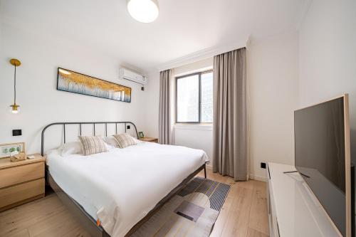 a bedroom with a bed and a flat screen tv at Tonight Homestay West Nanjing Road Branch Shanghai in Shanghai