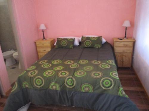 a bedroom with a bed with a green bedspread at Apart Hotel Curahue in Junín de los Andes