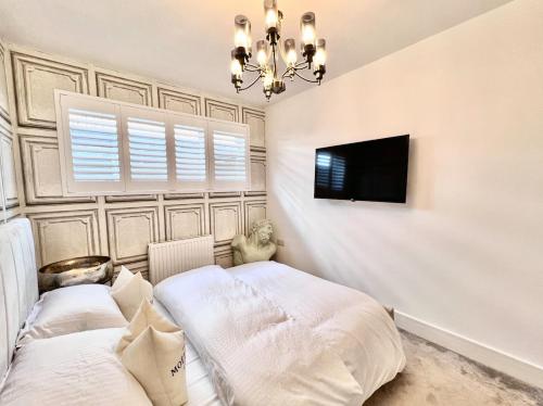 a bedroom with two beds and a flat screen tv at Southern Lane Beach House in Barton on Sea