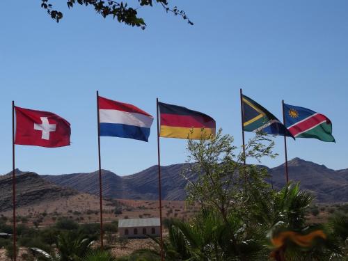 a group of flags on poles with mountains in the background at Rooisand Desert Ranch in Chausib