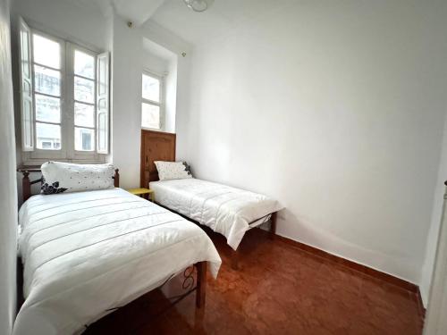 two beds in a small room with two windows at COZY Flat central Medina Tétouan 3BR 15 min airport ,Balcony in Tetouan