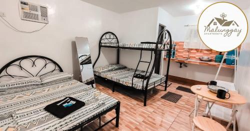 a room with two bunk beds and a table at Malunggay Apartments in Mariveles
