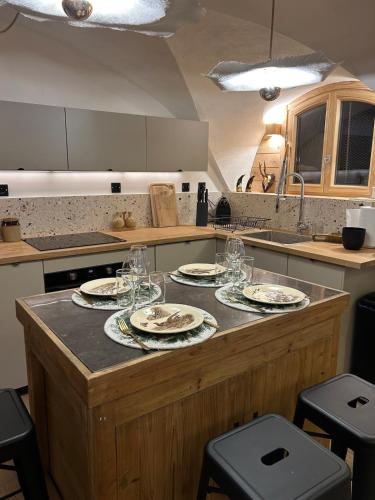 - une cuisine avec des assiettes et des verres à vin sur un comptoir dans l'établissement Appartement neuf à 300m des pistes, à Saint-Chaffrey