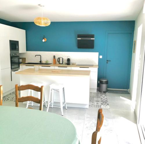 une cuisine avec une table et un mur bleu dans l'établissement Les Volets Verts, au Bois-Plage-en-Ré