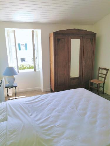 - une chambre avec un lit blanc et une armoire dans l'établissement Les Volets Verts, au Bois-Plage-en-Ré