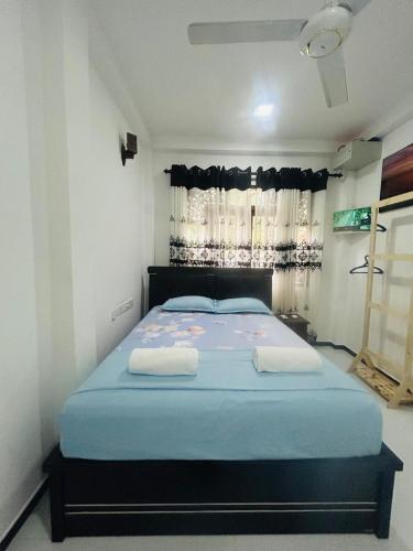 a bedroom with a bed with blue sheets and a window at Nisha Grean Heaven in Weligama