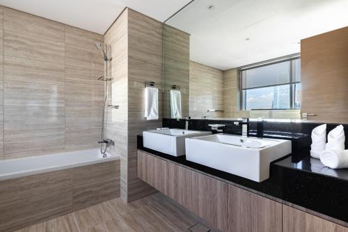 a bathroom with two sinks and a bath tub at Simply Comfort Vacation Homes Rental in Missoni Top Floor with Sea, Canal and Burj Khalifa Views in Dubai