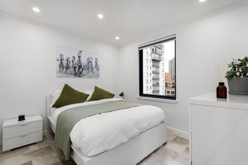 a white bedroom with a bed and a window at Central Luxury 3BR Apartment for up to 8 Guests in Melbourne
