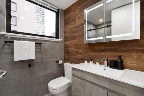 a bathroom with a toilet and a sink and a window at Central Luxury 3BR Apartment for up to 8 Guests in Melbourne