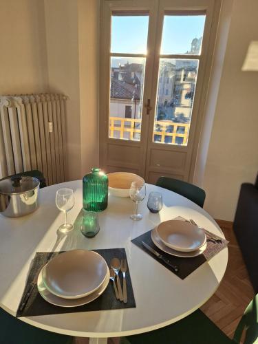 a white table with plates and glasses and a window at Chic Brand New Apartment at Palazzo Giuliani in Verbania in Intra