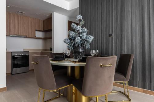 a dining room table with chairs and a vase of flowers at Simply Comfort Vacation Homes Rental in Missoni Top Floor with Sea, Canal and Burj Khalifa Views in Dubai