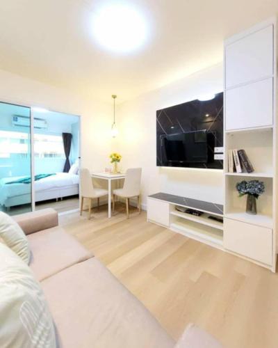 a living room with a large flat screen tv at Impact poppula P1 by เจี๊ยบ in Thung Si Kan