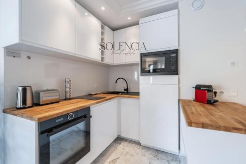 La cuisine blanche est équipée d'un évier et d'un réfrigérateur. dans l'établissement 2 pièces rue d'Antibes - Climatisation, à Cannes