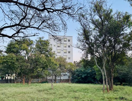 a white building in the middle of a field with trees at Truelife Whitefield - Premium 1 BHK Apartments - Prime location - Easy access to Main Rd - Metro - ITPL - Fast WiFi - Kitchen - Smart TV - Power backup - Park - Garden views in Bengaluru