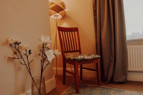 a chair and a lamp next to a vase with flowers at Newly Designed Home from Home in Retford in Retford