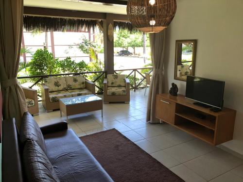 a living room with a couch and a television at Fleixeiras Eco Residence in Trairi