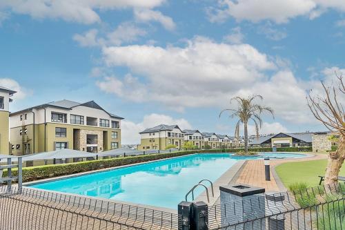 a large swimming pool with buildings in the background at Urban Waterfall Hideaway in Midrand