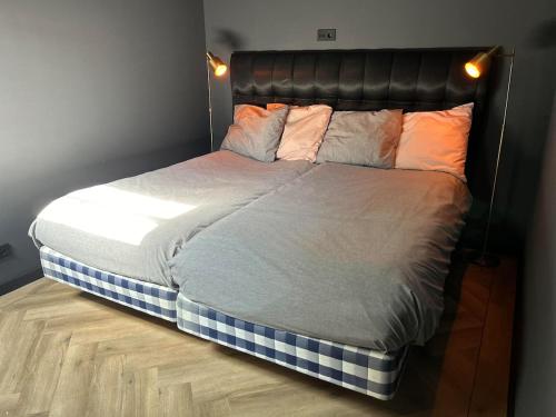 un letto con testiera nera e cuscini sopra di Studio aan de gracht a Delft