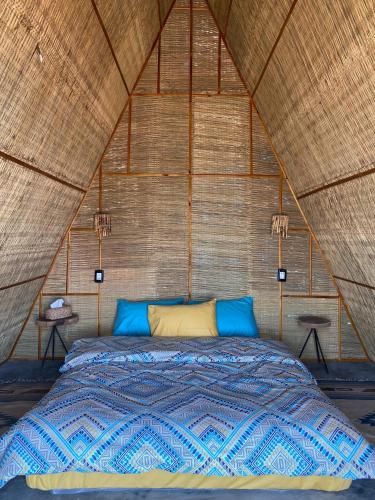 a bed in a tent with blue pillows at Sukoon Nuweibaa in Nuweiba