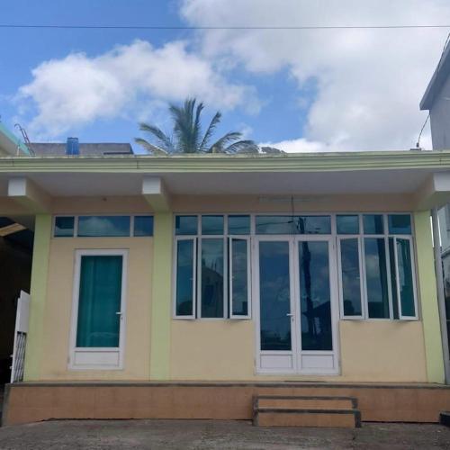 a yellow house with large windows and a palm tree at Spacious Mauritian Home Centrally Located in Highlands
